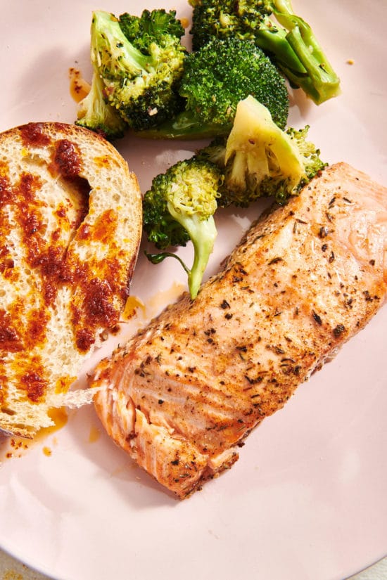 Herbed Salmon on a plate with broccoli and bread.