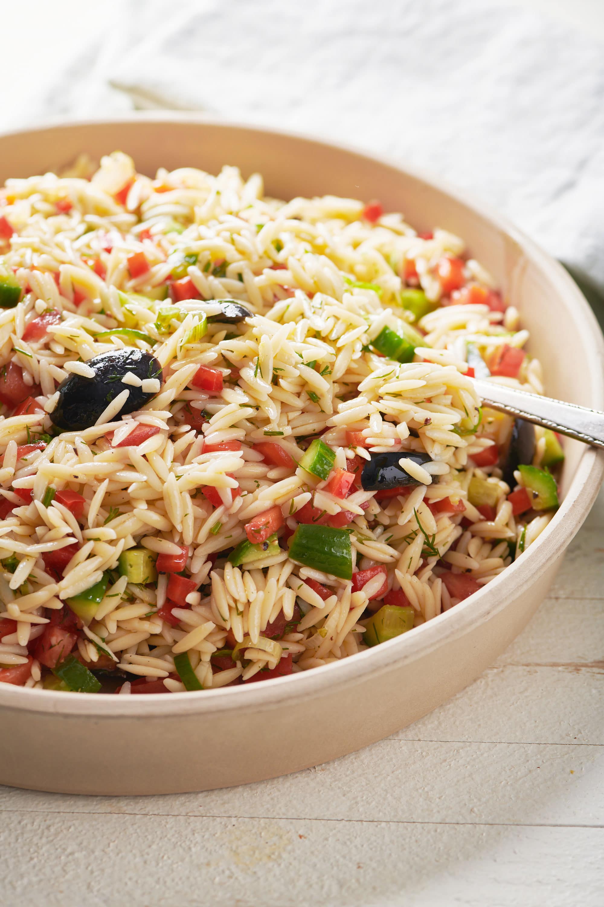 Spoon in a bowl of Greek Orzo Salad.