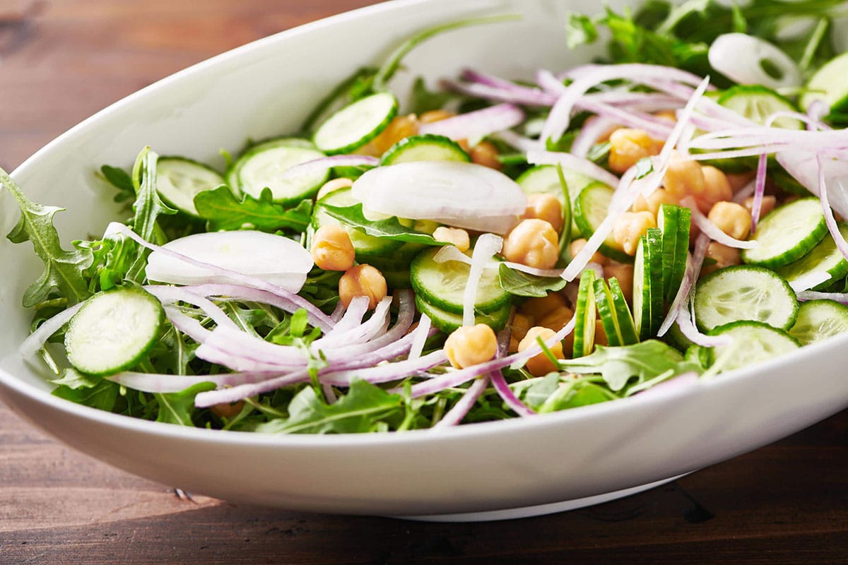 Green Salad with Chickpeas and Spicy Honey Tahini Dressing in white serving dish.