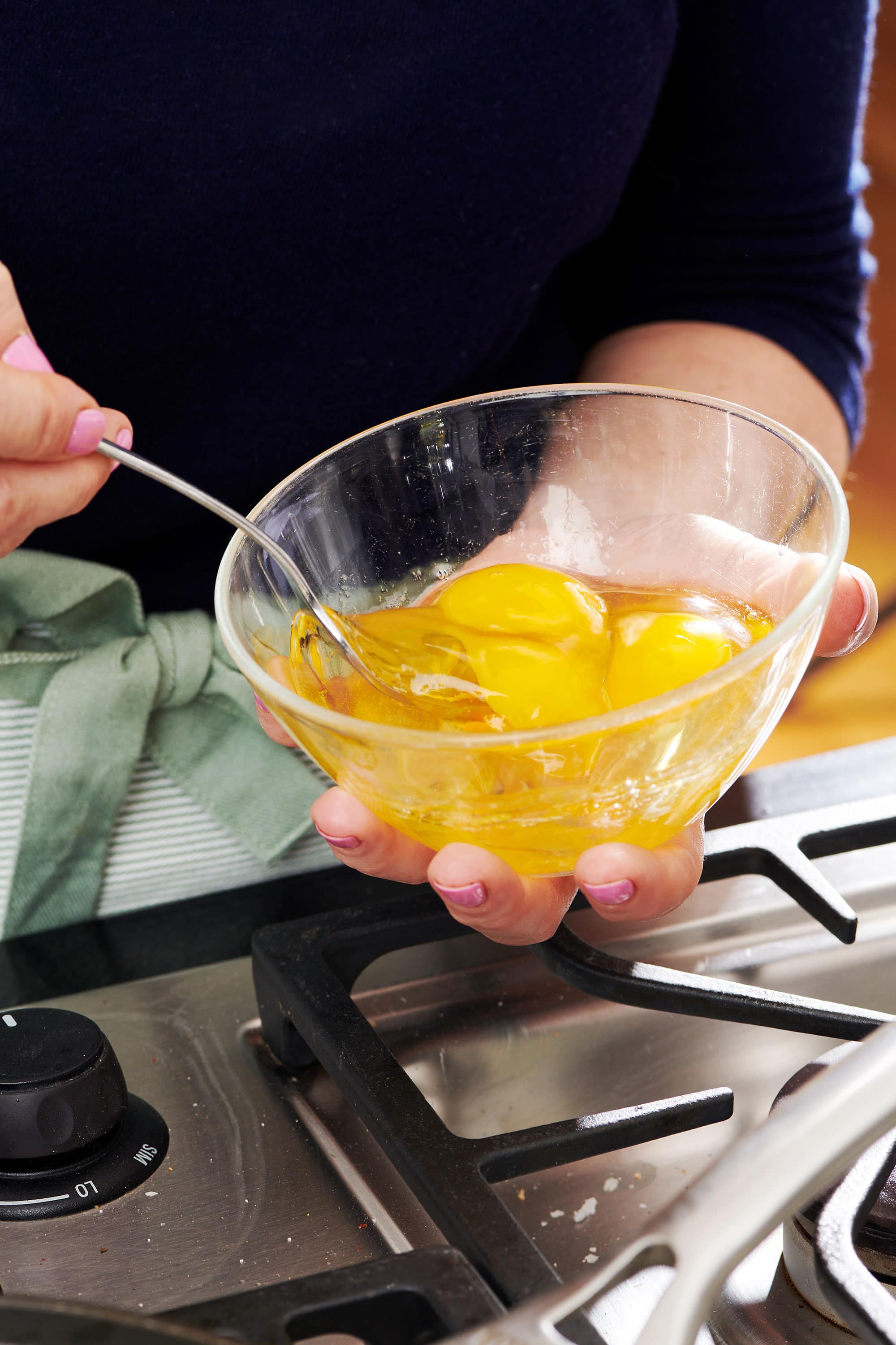 Woman holding a glass bowl of eggs.