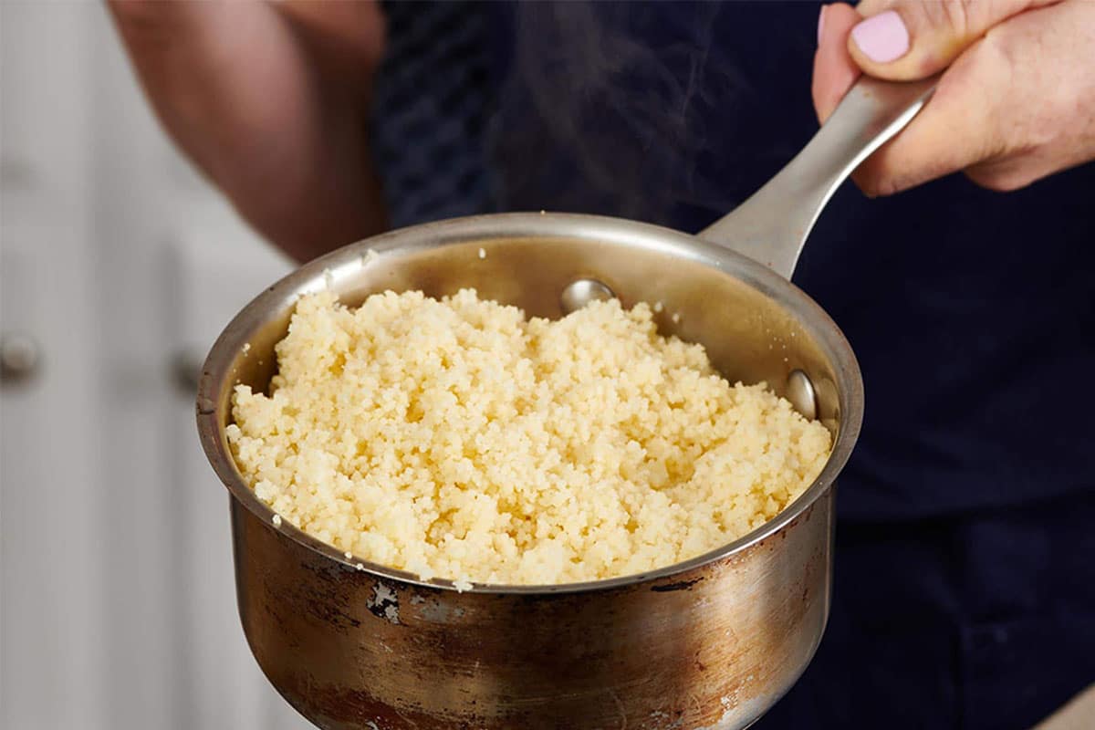 Cooked couscous in small pot.