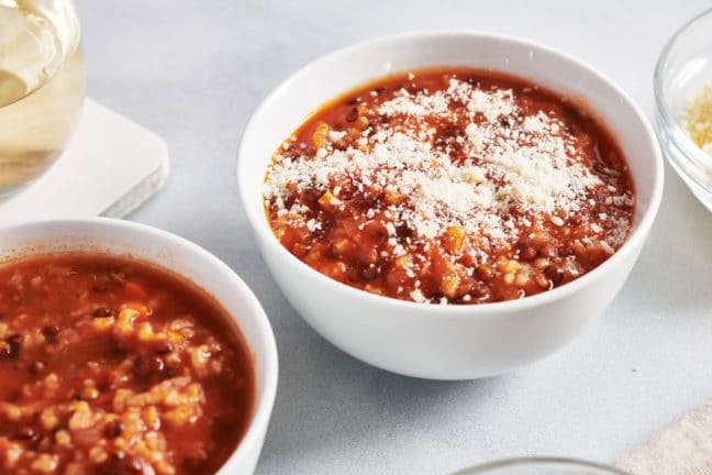 Bowl of Lentil Tomato Soup topped with parmesan cheese.