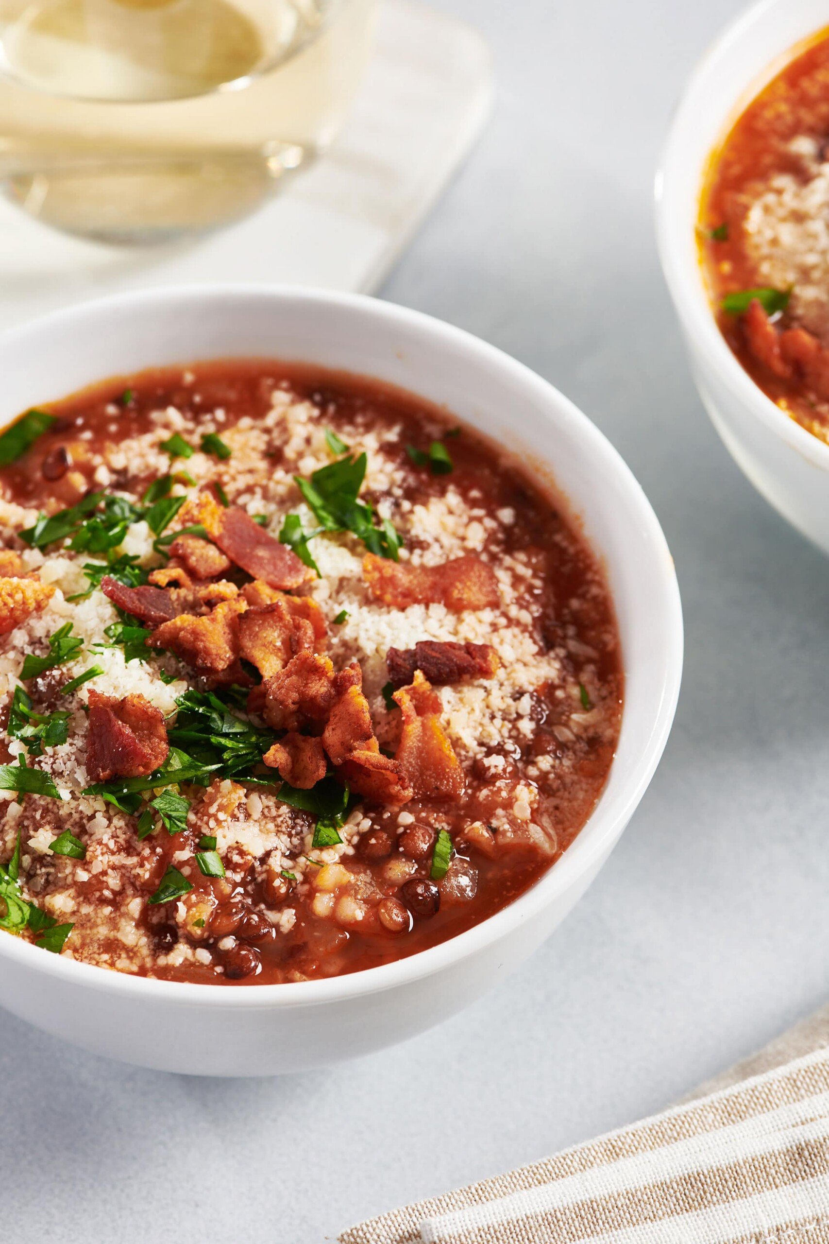 Lentil Tomato Soup in white bowl on table.