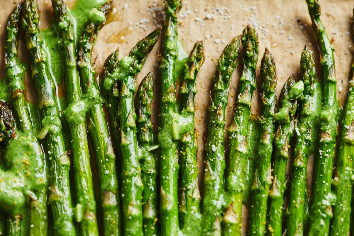 Roasted Asparagus on parchment paper and topped with Pesto Crème Fraiche.