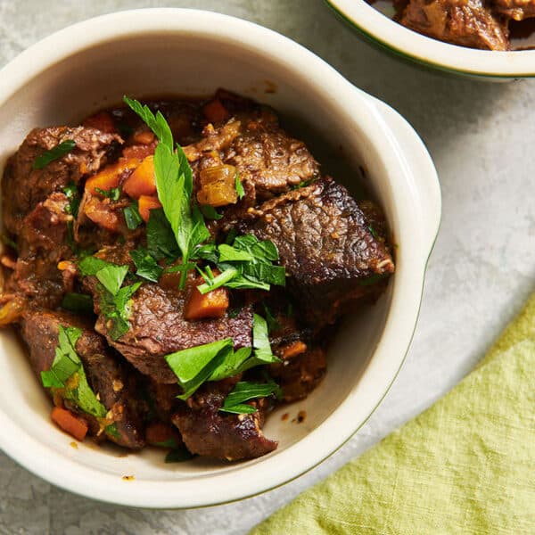 Beef stew in bowl garnished with fresh parsley.