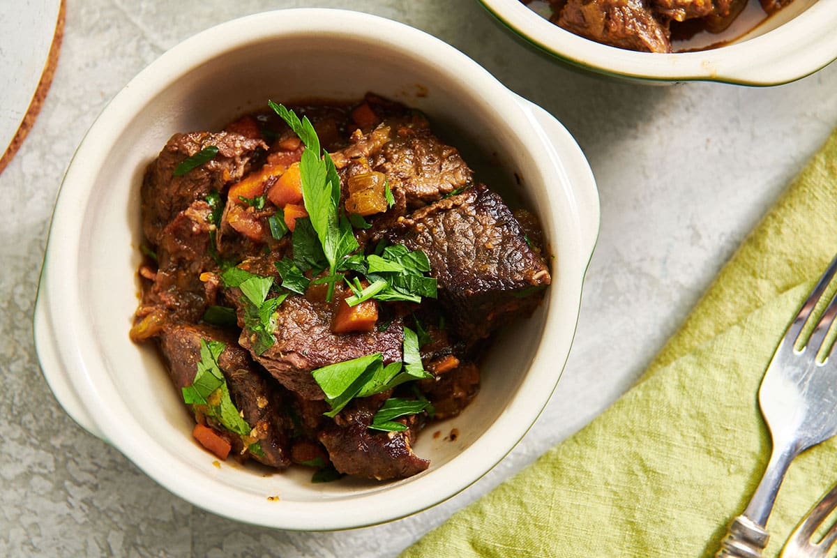 Beef stew in bowl garnished with fresh parsley.
