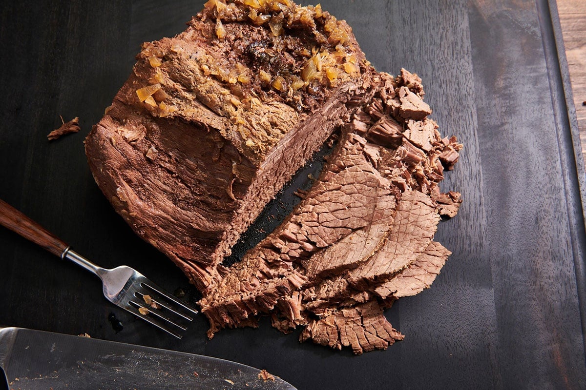 Partially-sliced Pot Roast on a wooden board.