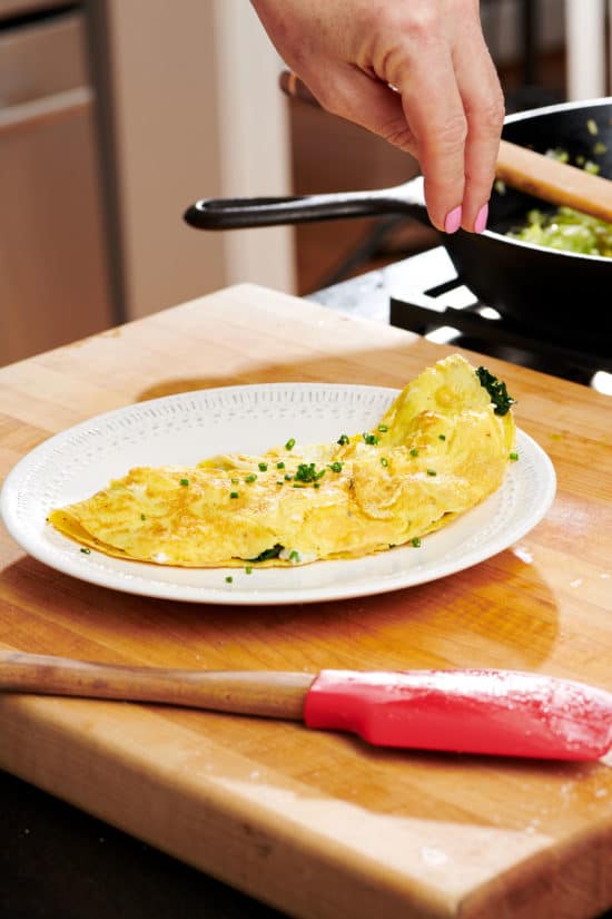 White plate with an Omelet on a wooden board.