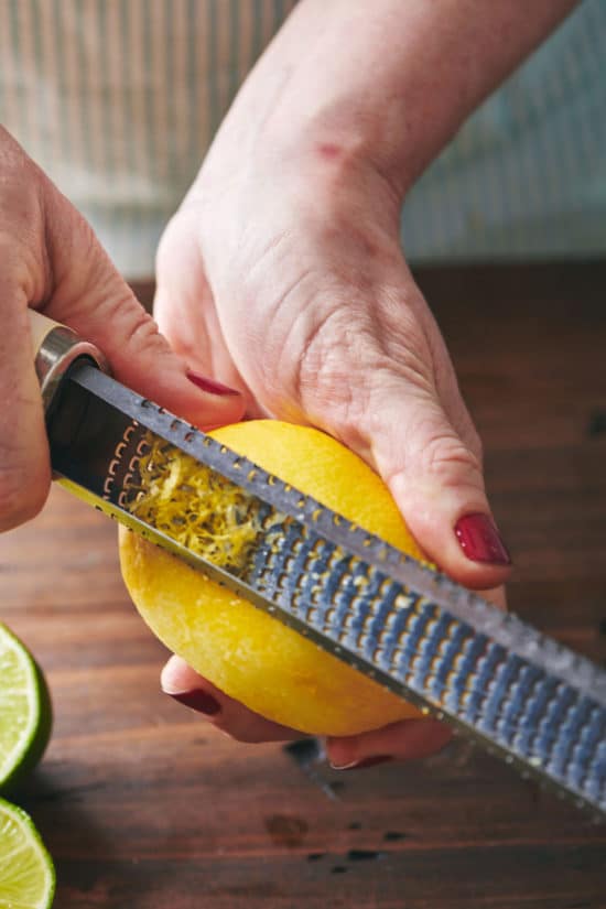 Woman using a microplane grater on a lemon.