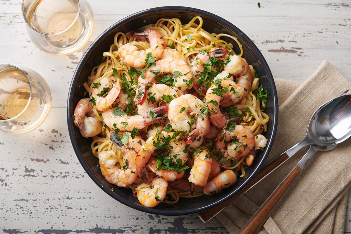 Shrimp scampi in black bowl on table.