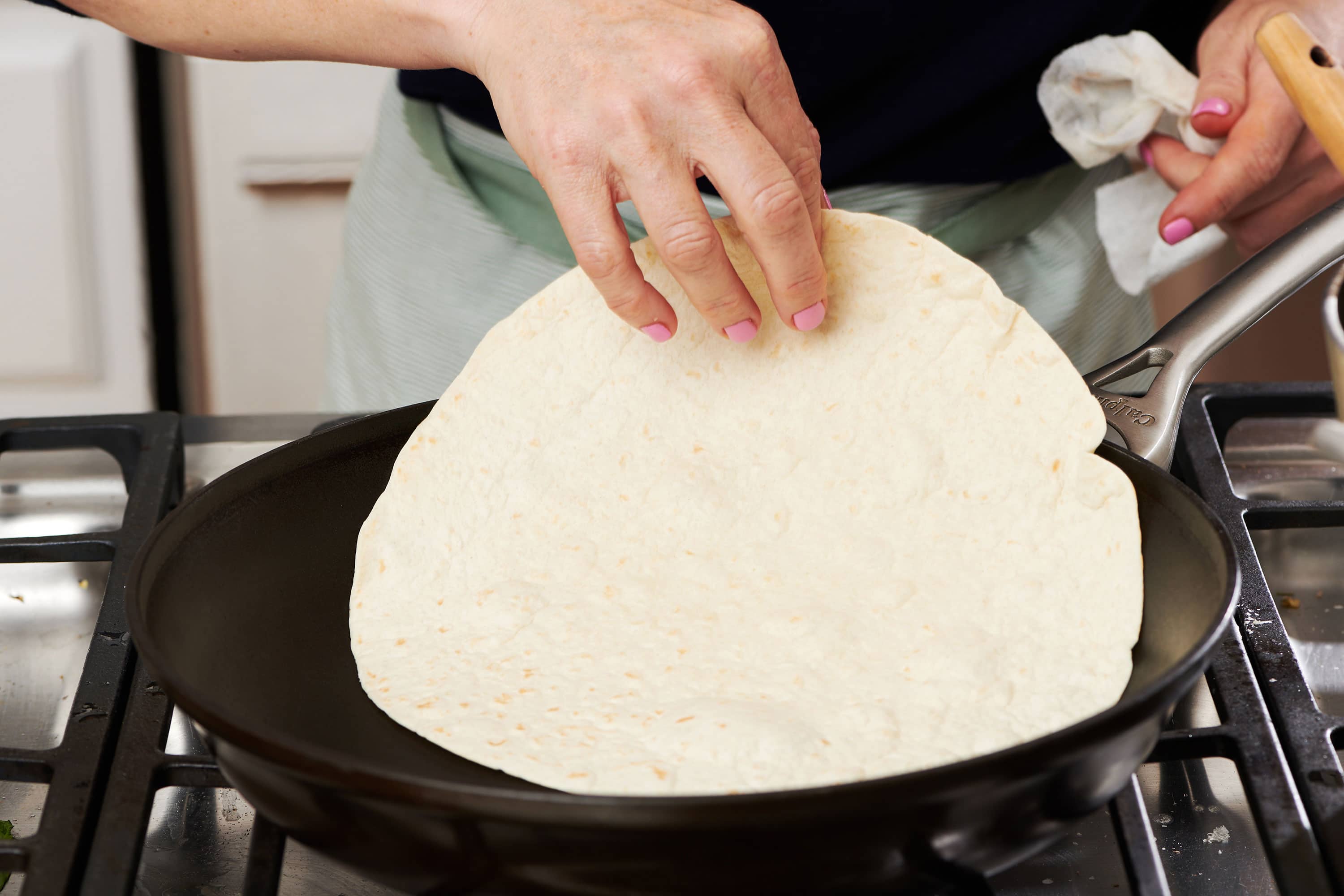 Placing tortilla in hot pan.