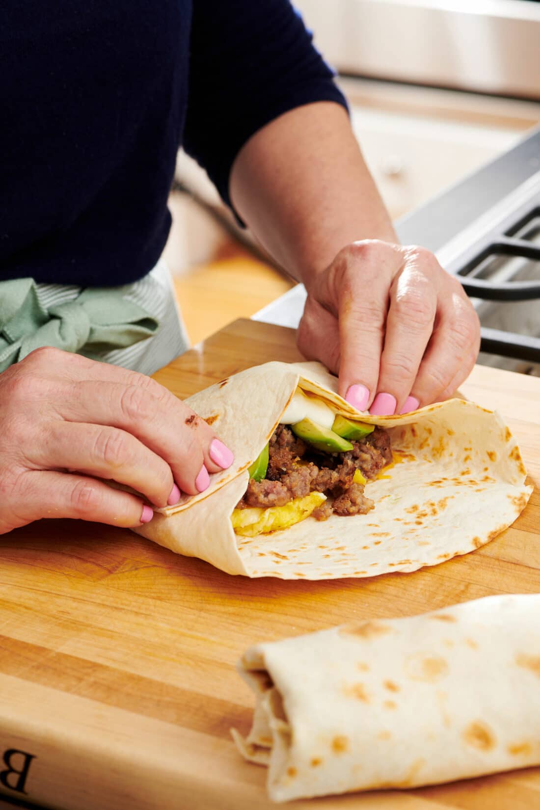 Woman rolling a tortilla to create a Breakfast Burrito.