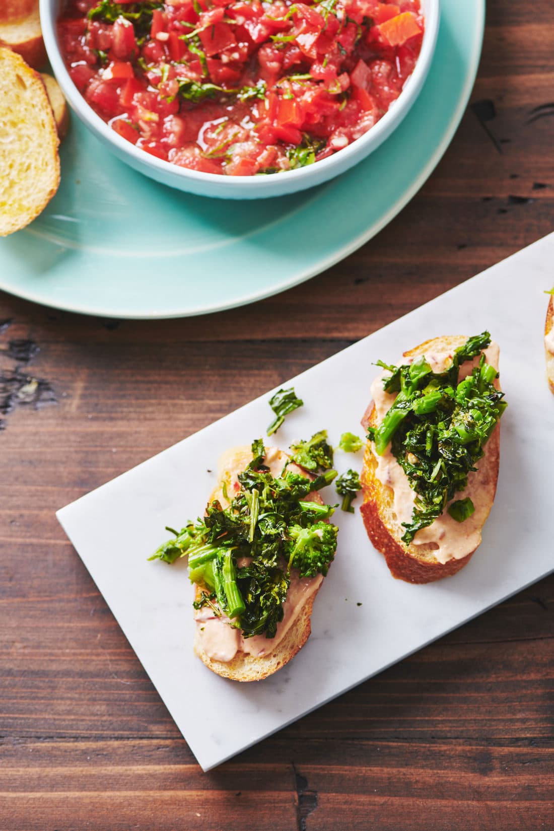 Broccoli Rabe Crostini with Chipotle Sauce on a plate on a wooden table.