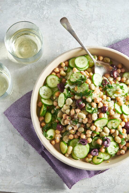 Table setting featuring chickpea and fava bean salad with wine