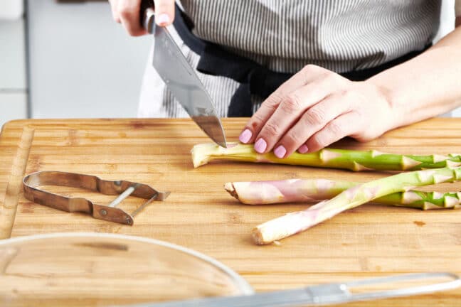 Woman cutting tough ends from asparagus stalks.