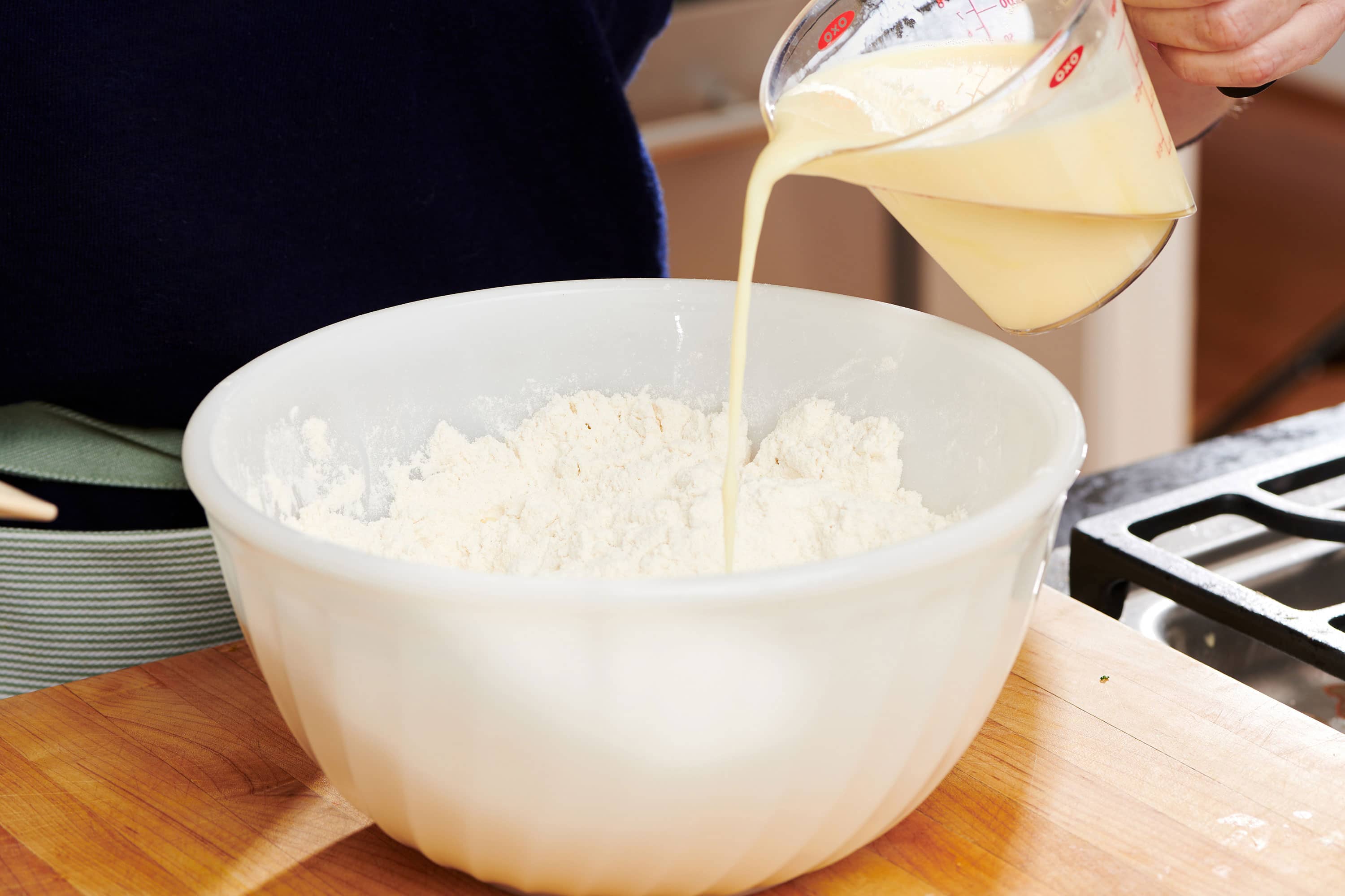 Buttermilk mixture pouring into a bowl of dry ingredients.