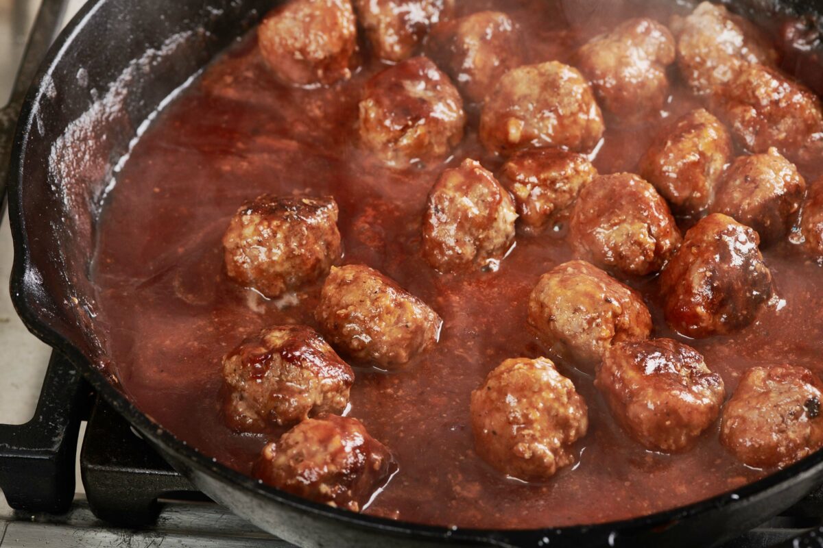 Meatballs in a skillet of sweet and sour sauce.