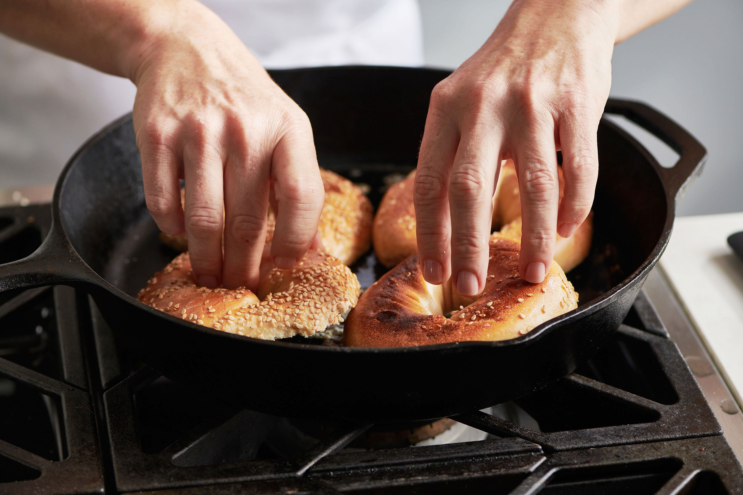 Woman toasting bagels in a pan.