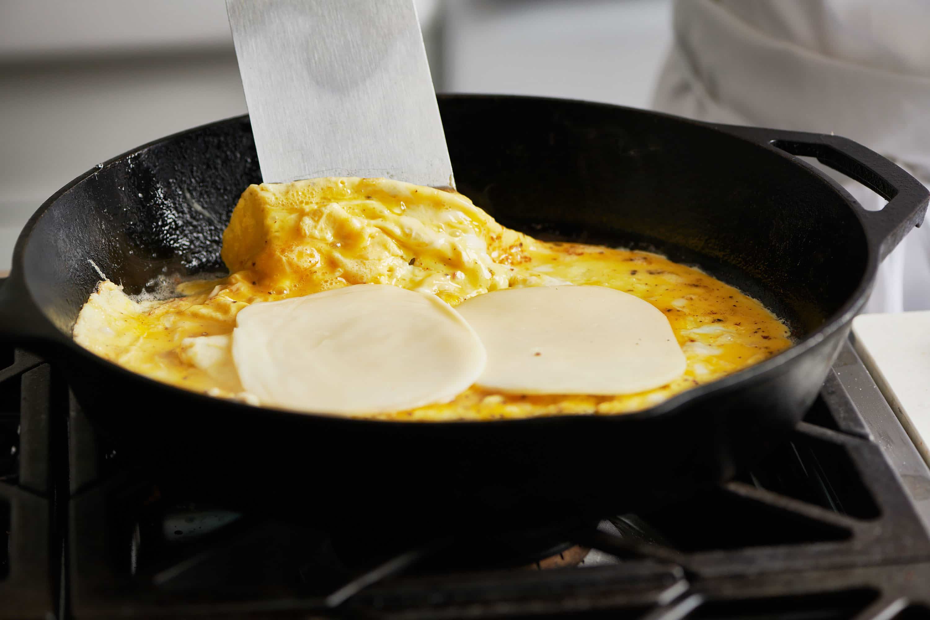 Eggs with cheese on top in a cast iron skillet.
