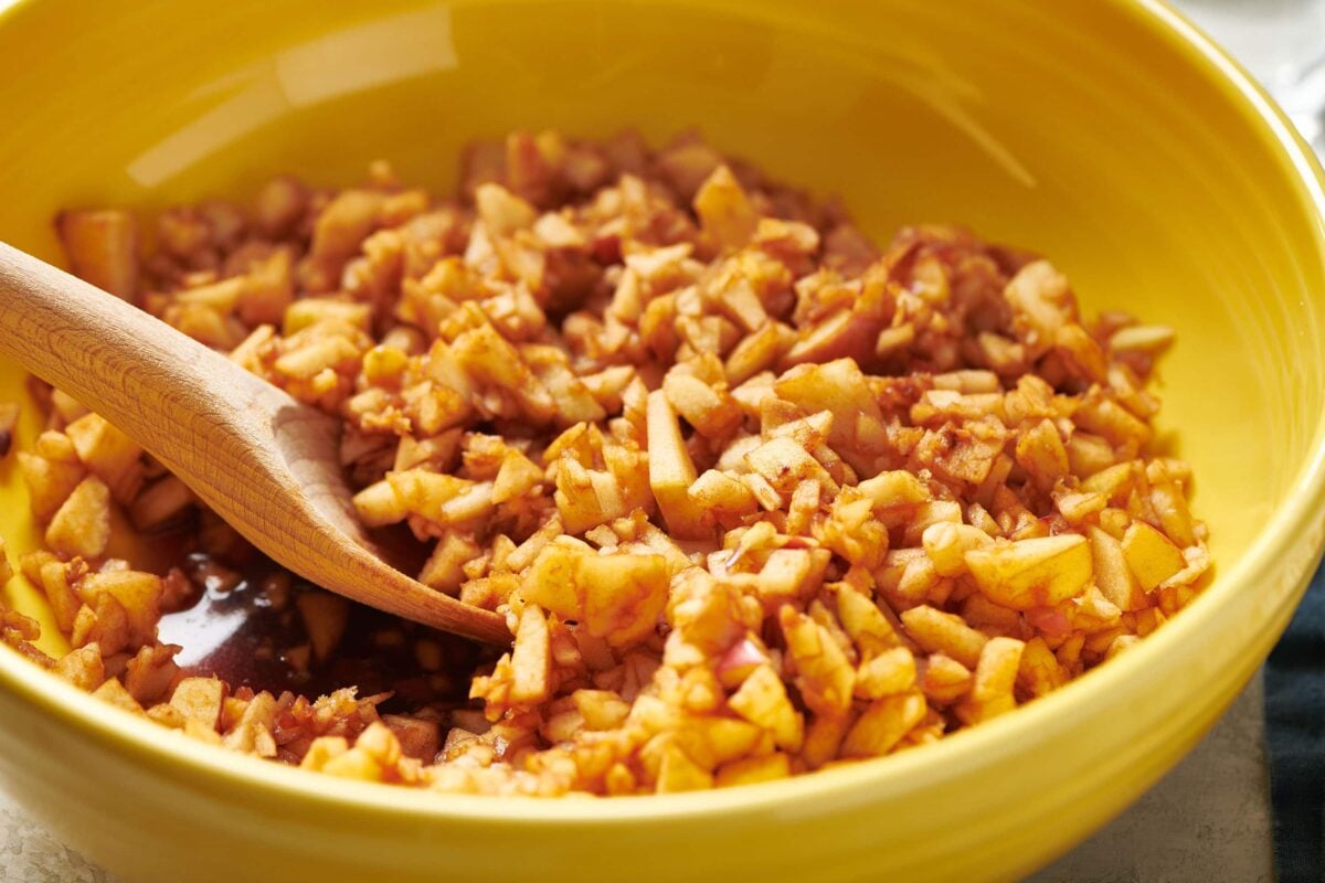 Homemade charoset in yellow bowl with wood spoon.