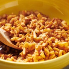 Homemade charoset in yellow bowl with wood spoon.
