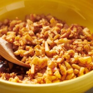 Homemade charoset in yellow bowl with wood spoon.