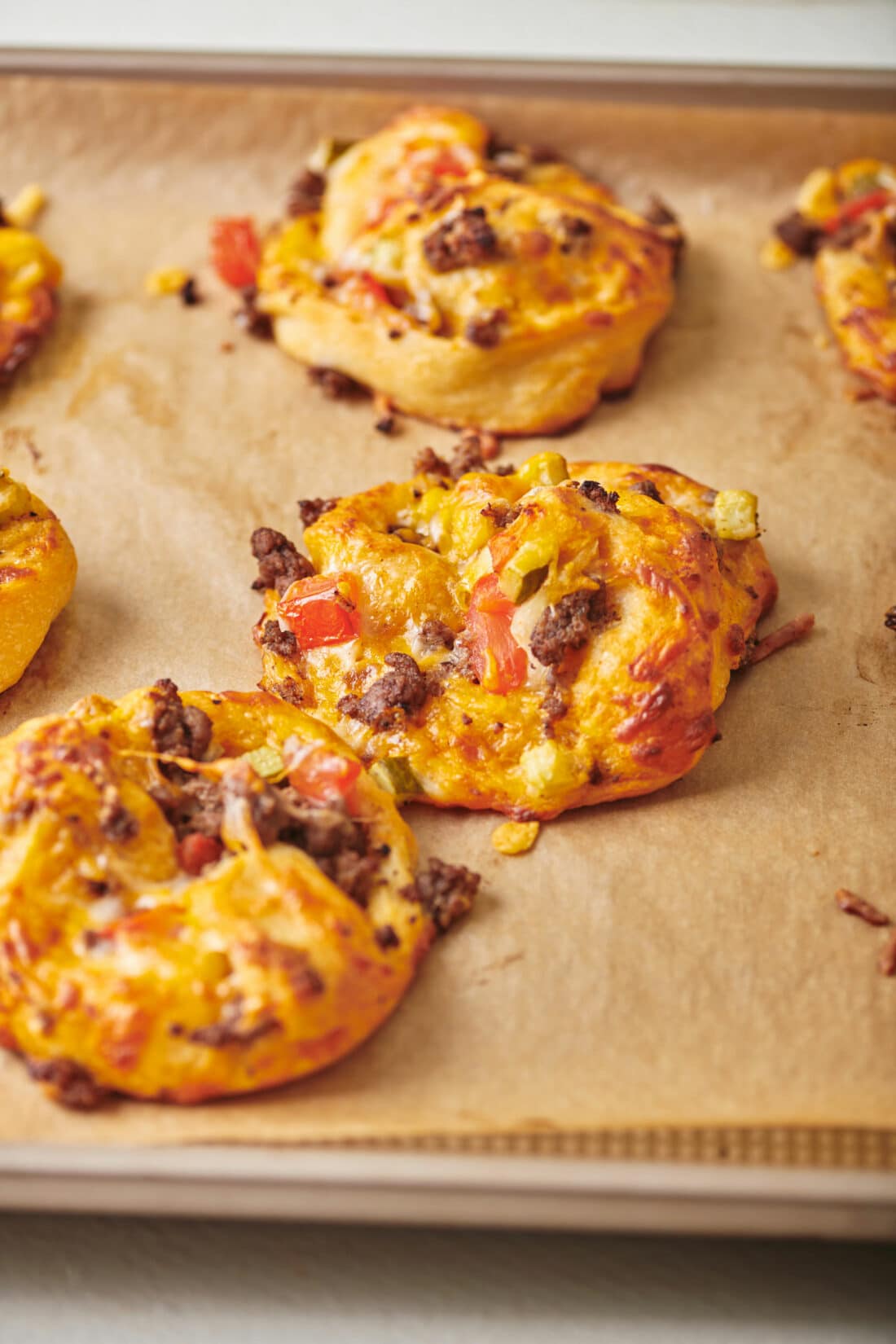 Cheeseburger Pizza Pinwheels on parchment paper.