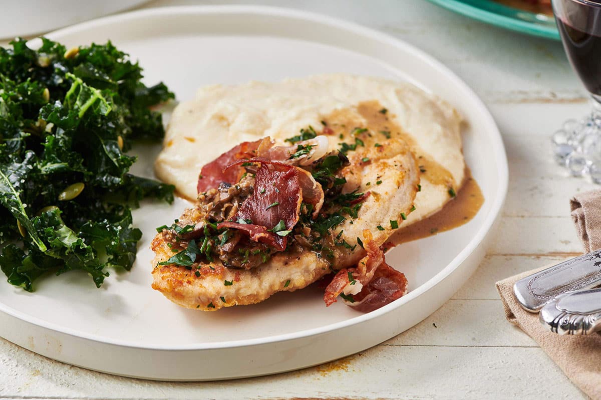Turkey Marsala on a white plate with greens.