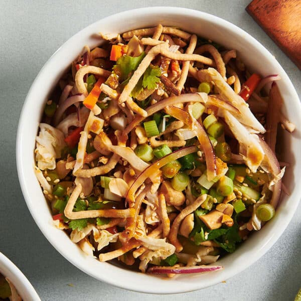 Bowls of Chinese Chicken Salad on table with drinks.