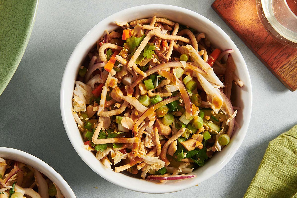 Bowls of Chinese Chicken Salad on table with drinks.