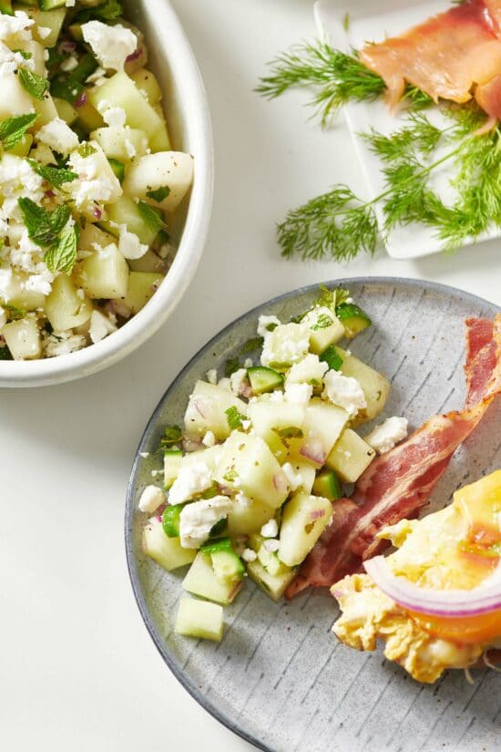 Honeydew-Cucumber Salad with Feta on a plate with bacon.