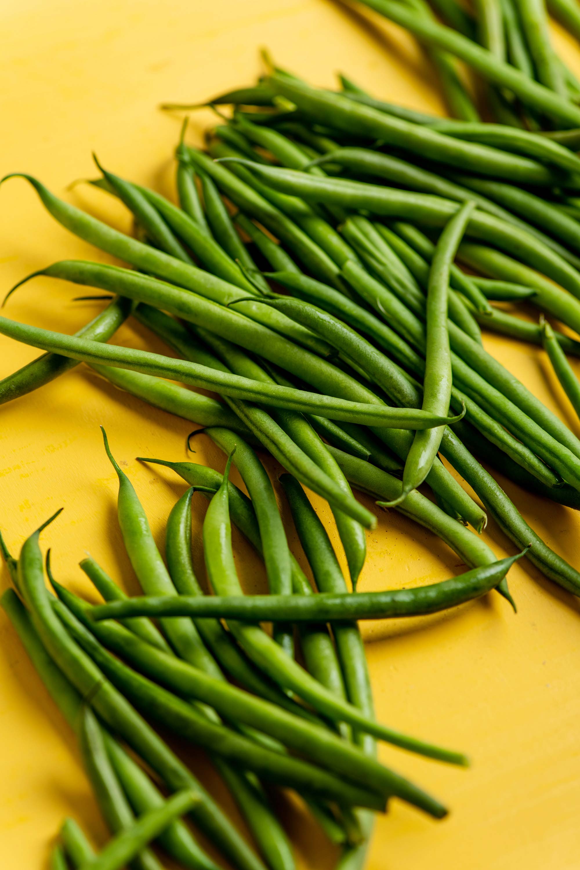 Haricot Verts on a yellow surface.