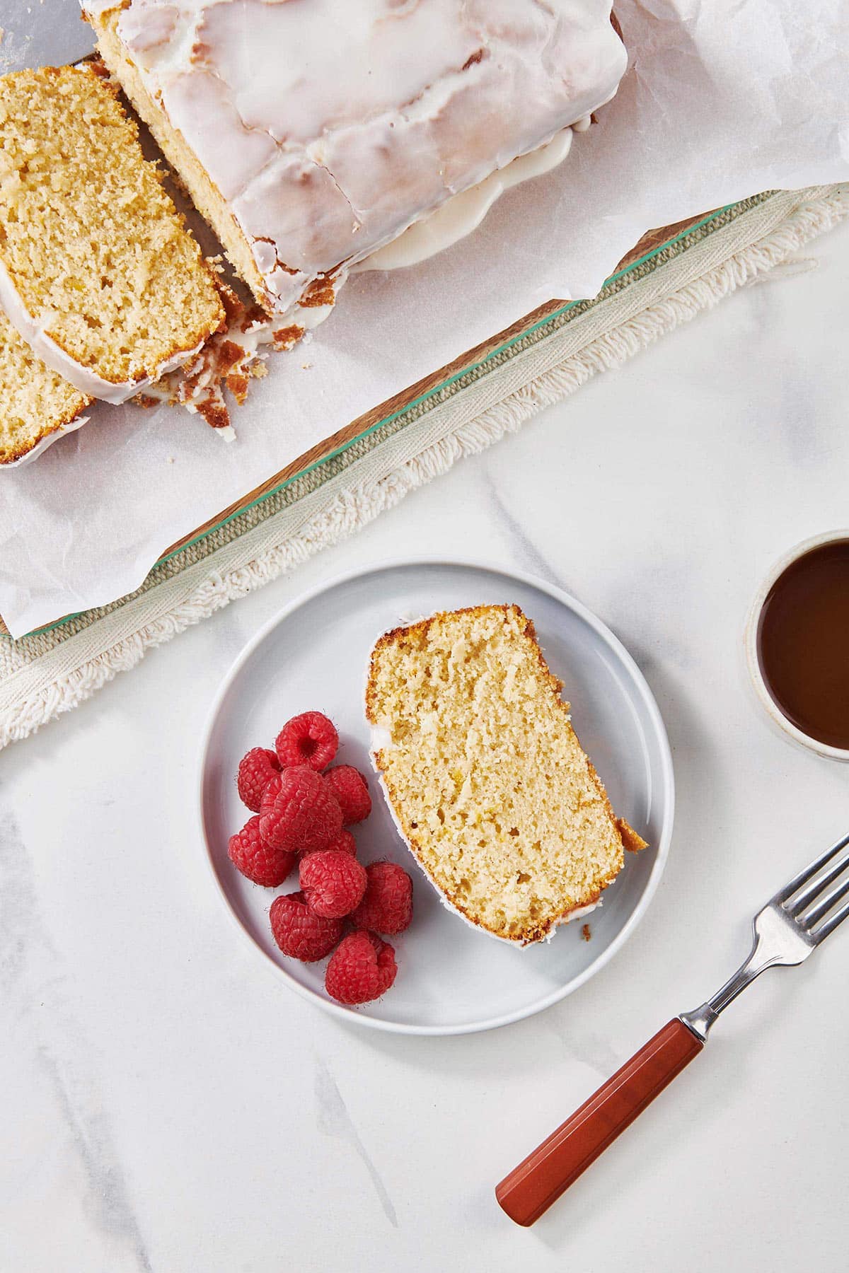 Raspberries on a plate with a slice of Lemon Cake.
