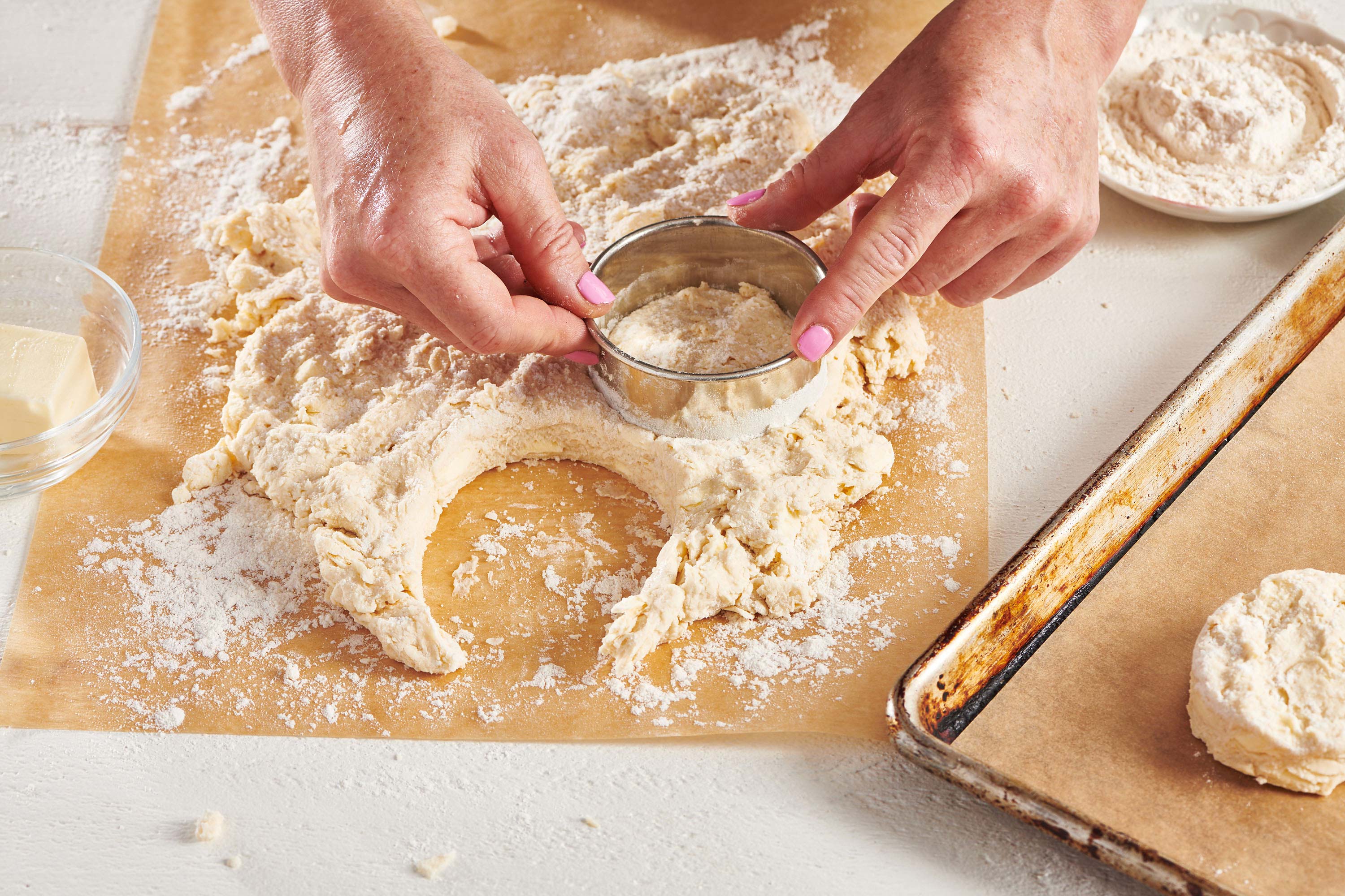 Woman cutting circles out of biscuit dough.