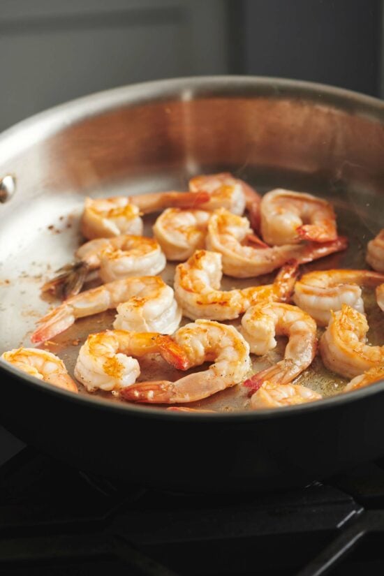 Shrimp being sauteed in a skillet.