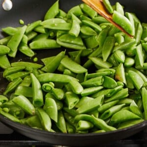 Sauteing sugar snap peas in pan.