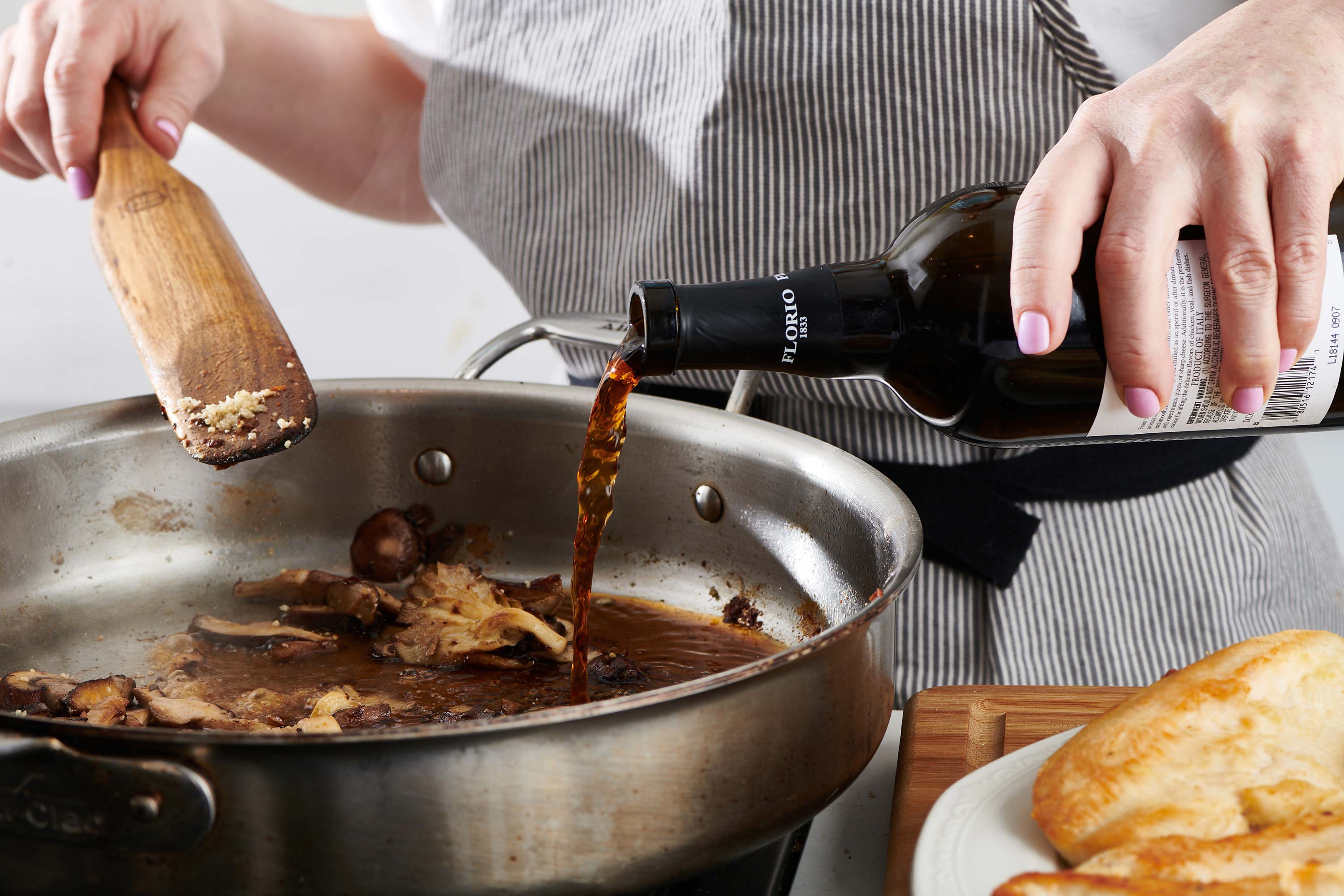 Woman pouring Marsala wine into a skillet.