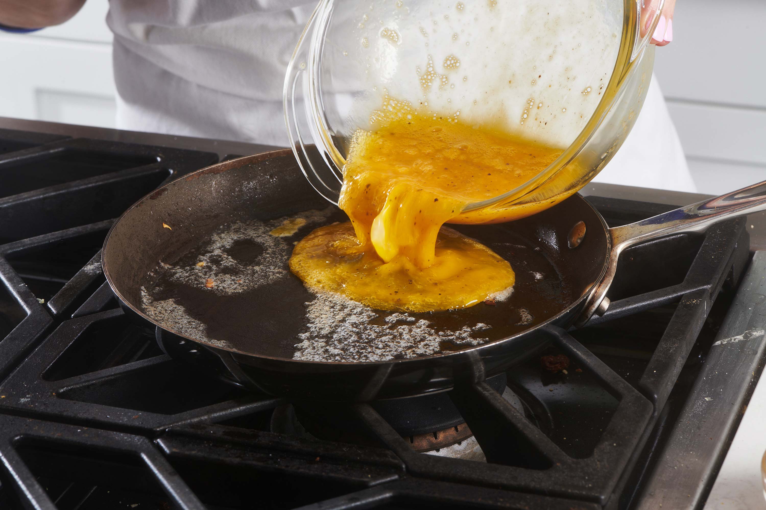 Beaten egg mixture pouring into a skillet.