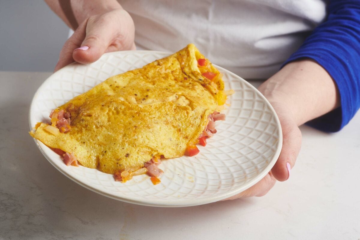 Woman holding a plate with a Denver Omelet.