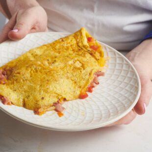 Woman holding a plate with a Denver Omelet.