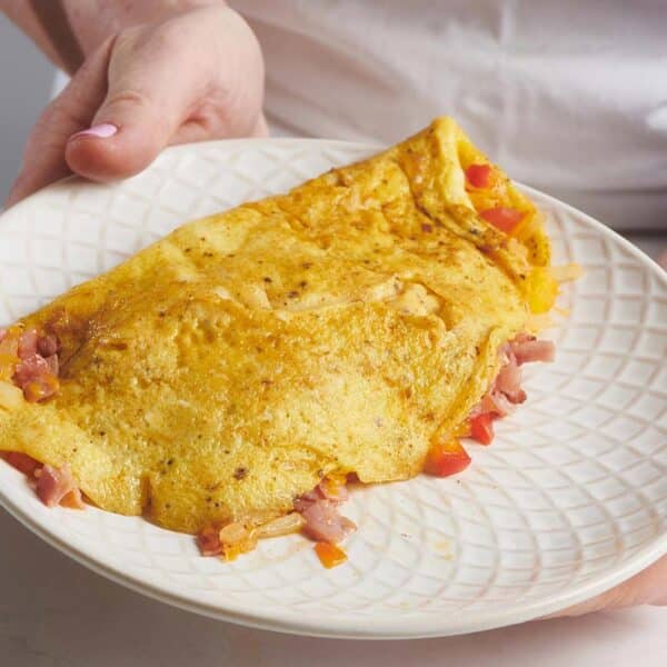 Woman holding a plate with a Denver Omelet.