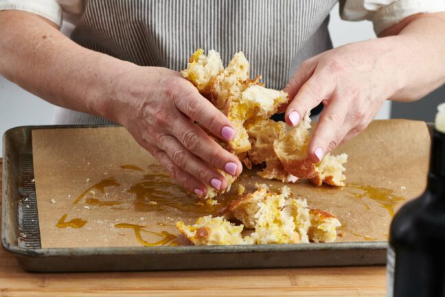 Woman mixing bread and oil with her hands.