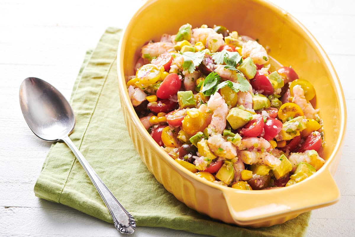 Light orange dish of Shrimp and Avocado Salad on a cloth napkin.