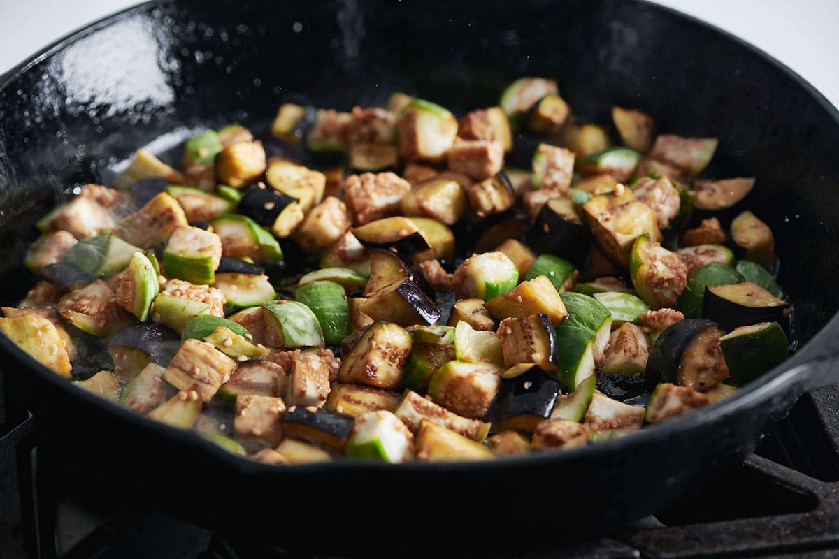 Cubed eggplant cooking in pan.