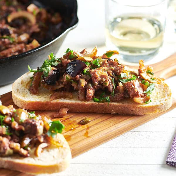 Two pieces of Caponata bruschetta on wood board.