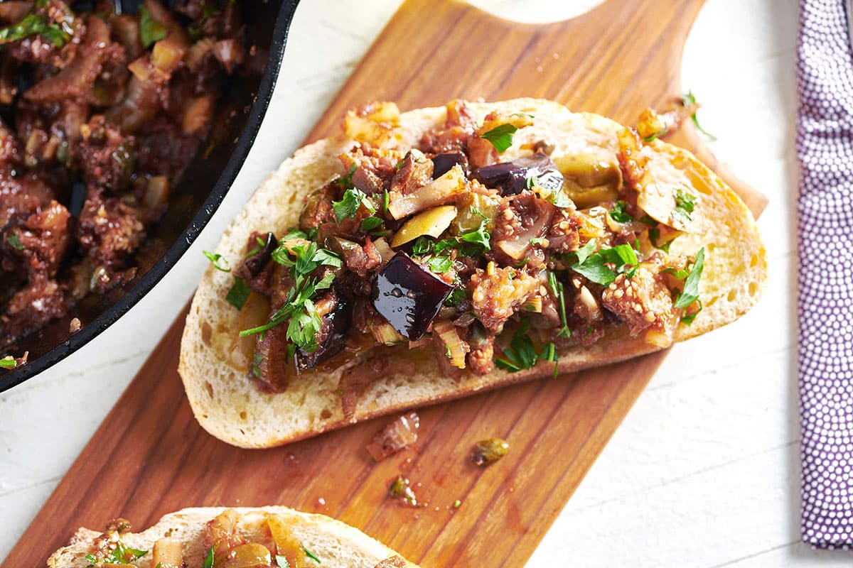 Caponata bruschetta on a wooden board.