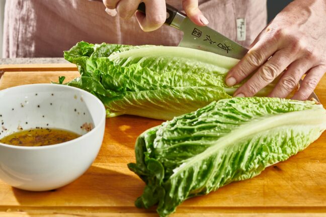 Woman slicing a head of Romaine.
