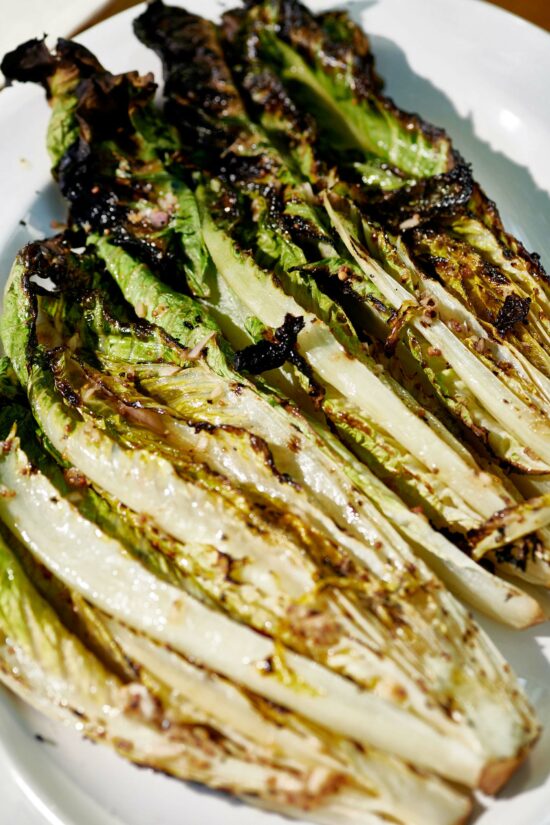 Several Grilled Romaine heads on a white plate.