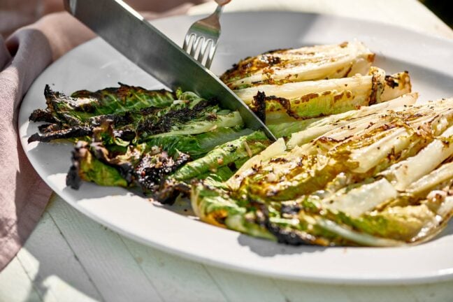 Knife slicing Grilled Romaine on a plate.