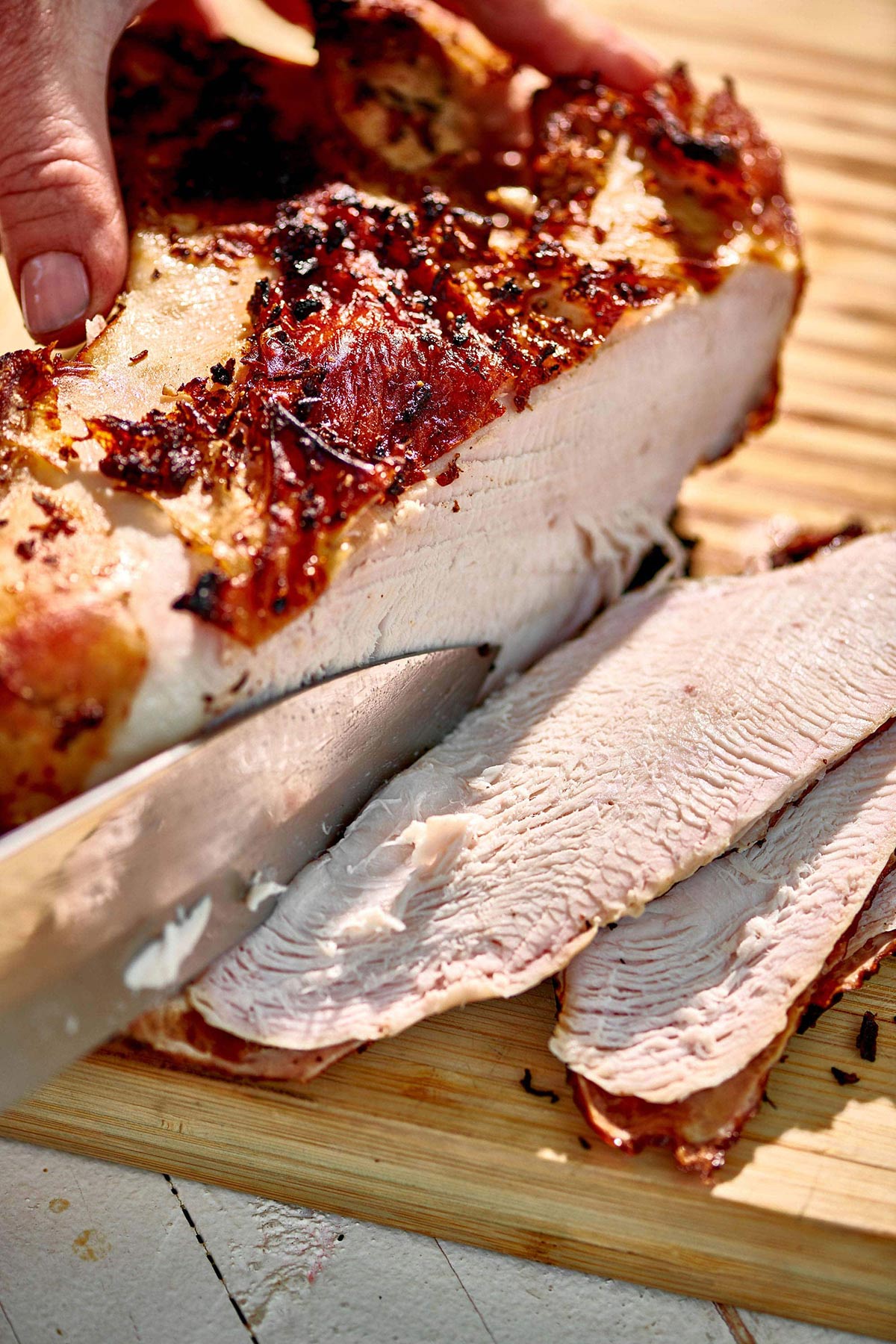 Woman slicing a Grilled Split Turkey Breast.